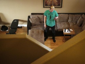 FILE - In this Thursday, Feb. 16, 2017, Randy Tussing, an Airbnb host, looks at his phone while standing in his home in Las Vegas. More than 340,000 people passed on Nevada's hotel rooms last year and opted instead to book a place to stay using the home-sharing service Airbnb. Officials in Las Vegas are expected to vote Wednesday, June 21, 2017, on a series of rules meant to crack down on the booming short-term rental industry in the city. The proposed rules include a special-use permit requirement, proof of liability insurance and placards displayed on the exterior of the properties. (AP Photo/John Locher, File)