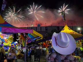 A visitor watches the fireworks display from the midway at the Calgary Stampede in Calgary, Saturday, July 9, 2016.