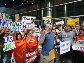 Michael Sciaraffo, center, (wearing blue) who was one of hundreds aboard a New York City subway train that lost power for nearly an hour earlier this month, speaks during a rush hour rally outside New York Gov. Andrew Cuomo's office, Wednesday, June 28, 2017, in New York. They were protesting following another accident of the New York subway on Tuesday, when the derailment in Harlem caused to toss people to the floor and forced hundreds of passengers to evacuate through dark tunnels. (AP Photo/Kathy Willens)