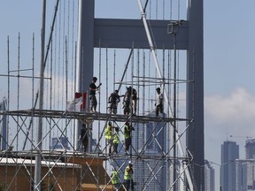 Backdropped by the 15 July Martyrs' Bridge, formerly known as Bosphorus Bridge and renamed to honour the victims of the July 15, 2016 failed coup attempt, workers construct a stage for the upcoming one-year anniversary, in Istanbul, Monday, July 10, 2017. On July 15, 2016, a group within the military, with tanks, fighter jets and helicopters, launched a failed plot to overthrow Turkey's president and government.(AP Photo/Lefteris Pitarakis)