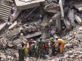 Workers try to release two bodies trapped in the rubble of collapsed Rana Plaza garment factory building in Savar, near Dhaka, Bangladesh on April 30, 2013.