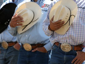 Hats in hand, cowboys acknowledge the playing of the anthem at the start of rodeo at the Calgary Stampede. There is a growing feeling in Alberta that the province is paying more than its fair share to the rest of the country.