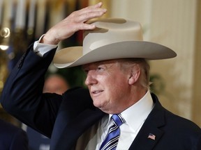 President Donald Trump tries on a Stetson hat during a "Made in America," product showcase featuring items created in each of the U.S. 50 states, Monday, July 17, 2017, at the White House in Washington. Stetson is base in Garland, Texas. (AP Photo/Alex Brandon)