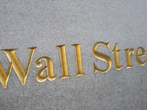 FILE - This Friday, Oct. 7, 2016, file photo shows a sign for Wall Street carved into a building located near the New York Stock Exchange. Declines in phone companies and real estate stocks are leading U.S. indexes lower in early trading on Wall Street, Thursday, July 6, 2017. Retailers and technology stocks were also down early Thursday. (AP Photo/Mark Lennihan, File)