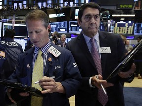 Traders Robert Charmak, left, and Mark Muller work on the floor of the New York Stock Exchange.