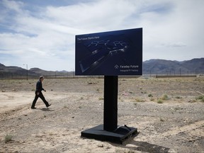 FILE - In this April 13, 2016, file photo, a man walks by a sign at an event to mark the start of construction for Faraday Future in North Las Vegas, Nev. Electric car maker Faraday Future said Monday, July 10, 2017 that it is deserting its plan to construct a $1 billion manufacturing plant in southern Nevada eight months after suspending the project and sinking at least $120 million into it. (AP Photo/John Locher, File)
