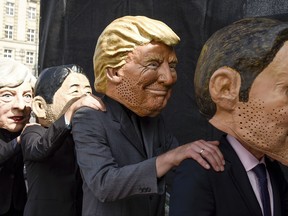 Demonstrators  against the G20 Summit stand on stage wearing masks depicting  from left : British Prime Minister Theresa May,  Japan's Prime Minister Shinzo Abe, US President Donald Trump and French President Emmanuel Macron, in Hamburg, Germany, Sunday, July 2, 2017.  (Axel Heimken/dpa via AP)