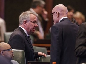 Illinois State Rep. Steve Andersson, R-Geneva, left, talks with Illinois State Rep. Greg Harris, D-Chicago, right, on the floor of the Illinois House during the overtime session at the state Capitol, Sunday, July 2, 2017, in Springfield, Ill. The Illinois House has approved an income tax increase as part of a plan to end the nation's longest budget standoff. (Justin L. Fowler/The State Journal-Register via AP)