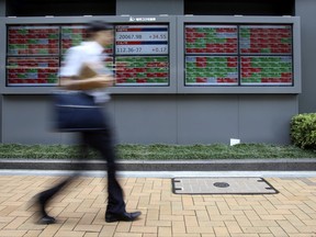 A man walks by an electronic stock board of a securities firm in Tokyo, Monday, July 3, 2017. Asian stock markets were mixed Monday after a Japanese manufacturing indicator showed conditions improving, a glimmer of upbeat news for Prime Minister Shinzo Abe after a resounding defeat of his ruling Liberal Democratic Party in Tokyo municipal elections on Sunday. (AP Photo/Koji Sasahara)