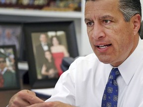 FILE - In this April 17, 2015, file photo, Nevada Gov. Brian Sandoval sits in his office at the capitol in Carson City, Nev. A bipartisan team of political leaders in Nevada is planning to host a national conversation on clean energy this fall. Former Democratic Senate Majority Leader Harry Reid and Republican Gov. Sandoval on Wednesday, July 12, 2017, announced the annual Las Vegas summit would be held Oct. 13. (AP Photo/Cathleen Allison, File)