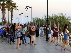 In this Friday, June 30, 2017 photo, tourists takes pictures as the sun sets over the Mediterranean Sea in Beirut, Lebanon. The tourism industry in Lebanon is on the rebound, thanks in no small part to the misfortunes of its Middle East neighbors, engulfed by wars, chaos and political upheaval. (AP Photo/Hassan Ammar)