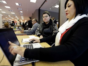 FILE - In this Friday, Nov. 14, 2014 file photo, Affordable Care Act health insurance marketplace navigator Leticia Chaw, right, helps gather information for Jennifer Sanchez to re-enroll in a health insurance plan in Houston. Shoppers will have fewer places to turn for help signing up for coverage on the ACA's insurance exchanges with the announcement in July 2017 that President Donald Trump's administration ended contracts that brought assistance into libraries, businesses and urban neighborhoods in 18 cities. (AP Photo/David J. Phillip)