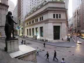 FILE - In this Oct. 8, 2014, file photo, people walk to work on Wall Street beneath a statue of George Washington, in New York. U.S. stocks are mostly higher early Monday, July 17, 2017, as retailers and clothing companies rise while banks slip along with interest rates. Technology companies continue to recover after a steep skid that lasted about a month. Stock indexes closed at record highs Friday and are adding to their gains. (AP Photo/Mark Lennihan, File)