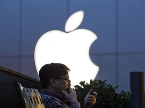 FILE - In this Friday, May 13, 2016, file photo, a man uses his mobile phone near an Apple store in Beijing. On Wednesday, July 12, 2017, Apple announced it will open a data center in mainland China with ties to the country's government, raising concerns about the security of iCloud accounts that store personal information transferred from iPhones, iPads and Mac computers there. (AP Photo/Ng Han Guan, File)