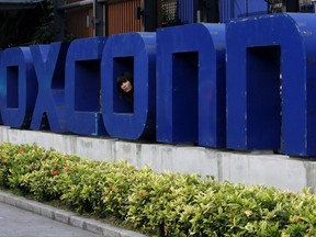 FILE - In this Thursday, May 27, 2010, file photo, a worker looks out through the logo at the entrance of the Foxconn complex in the southern Chinese city of Shenzhen. Two Republican state lawmakers said Thursday, July 20, 2017, that Wisconsin could announce it has landed a deal for Taiwanese iPhone manufacturer Foxconn to locate in the state as soon as the end of the month. (AP Photo/Kin Cheung, File)