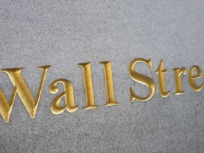 FILE - This Friday, Oct. 7, 2016, file photo shows a sign for Wall Street carved into a building located near the New York Stock Exchange.  U.S. stocks followed other markets lower on Friday, July 28, 2017 after Amazon and several other big companies reported quarterly results that underwhelmed investors. (AP Photo/Mark Lennihan, File)