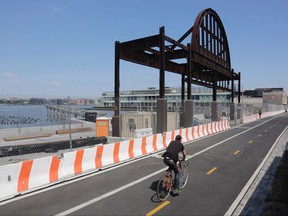 In this July 21, 2017 photo, a bicyclist riding along the Hudson River Greenway passes Pier 51 on the Hudson River in New York City. Media mogul Barry Diller and his wife, Diane von Furstenberg, want to transform the site into a futuristic island park and performance space but their project is running into opposition from real estate developer Douglas Durst.  (AP Photo/Bebeto Matthews)