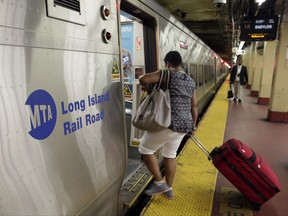 FILE- In this July 15, 2014 file photo, passengers board a Long Island Rail Road train, in New York's Penn Station. Dubbed the "summer of hell," by New York's governor, an eight-week infrastructure renovation project beginning Monday, July 10, 2017, at the nation's busiest train station is expected to cause major disruptions for hundreds of thousands of commuters.  (AP Photo/Richard Drew, File)