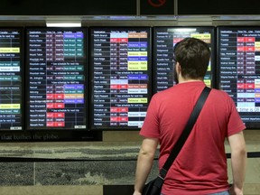 A New Jersey Transit passenger checks the schedules in New York's Penn Station, Tuesday, July 18, 2017. New Jersey Transit says some trains have been canceled this week because engineers are choosing not to work under the terms of their contract amid the summer-long repair work at Penn Station. (AP Photo/Richard Drew)