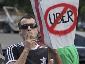In this photo taken on June 11, 2014, a taxi driver protests against Uber during a 24 hour taxi strike in Madrid, Spain. In a statement Saturday July 22, 2017, the city of Madrid has asked Spain's anti-trust watchdog to investigate whether Uber's new airport transport service violates fair competition laws saying tariffs may violate several articles of the Law of Unfair Competition and consumer rights if they are below the cost of providing the service. (AP Photo/Paul White)