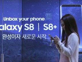 In this Wednesday, July 26, 2017 photo, a woman walks by an advertisement of Samsung Electronics' Galaxy S8 smartphone at its shop in Seoul, South Korea. Samsung Electronics on Thursday, July 27, said its second-quarter profit surged 85 percent to record high thanks to memory chips. (AP Photo/Ahn Young-joon)