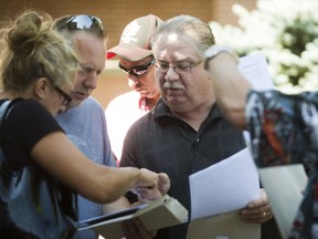 Workers at the closing Siemens wind turbine blade plant in Tillsonburg emerge from their meeting and check their severance packages on Tuesday.