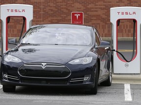 In this Saturday, June 24, 2017, photo, a Tesla car recharges at a charging station at Cochran Commons shopping center in Charlotte, N.C. On Monday, July 3, 2017, Tesla CEO Elon Musk sent out a tweet saying that the company anticipates reaching production of 20,000 Model 3 cars per month in December. That figure is less than previous estimates. Tesla's shares are shaping up to possibly have their worst week of the year so far as lower-than-expected production, increased competition and a review from an industry group weigh on the electric carmaker. (AP Photo/Chuck Burton)