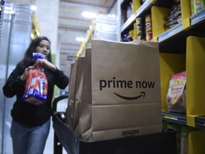 A staff member collects merchandise for customers' orders from shelves at the newly-opened Amazon Prime Now facility.