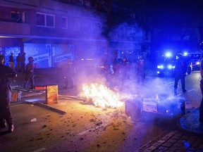 Policemen stand guard in the so-called 'Schanzenviertel' area  next to a burning barricade, on the sidelines of the G-20 summit, early Sunday, July 9, 2017, in Hamburg.  Rioters set up street barricades, looted supermarkets and attacked police with slingshots and firebombs. (Daniel Bockwoldt/dpa via AP)
