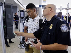 In a June 29, 2017, photo, U.S. Customs and Border Protection Officer Sanan Jackson, right, helps a passenger navigate the new face recognition kiosks at gate E7 for a United Airlines flight to Tokyo at Bush Intercontinental Airport in Houston. The Trump administration intends to require that American citizens boarding international flights submit to face scans, something Congress has not explicitly approved and privacy advocates consider an ill-advised step toward a surveillance state. (Michael Wyke/Houston Chronicle via AP)