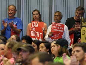 Audience members applaud as they look on during public comments at a Seattle City Council meeting where a new city income tax on the wealthy was being considered Monday, July 10, 2017, in Seattle. Seattle's highest earners would become the only Washington state residents to pay an income tax under the proposal that is designed to open a broader discussion about whether the wealthy pay their fair share in this booming city. (AP Photo/Elaine Thompson)