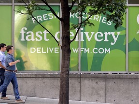 In this Tuesday, July 11, 2017, photo, people walk past a Whole Foods Market, just down the street from the Amazon headquarters, in Seattle. Amazon, already a powerhouse in books, shoes, streaming video, electronics and just about everything else, will bind its customers even more closely once it completes its $13.7 billion bid for the organic grocer Whole Foods. Although antitrust lawyers believe the deal will get approved, many customers and experts alike worry about two big companies combining into a bigger one. (AP Photo/Elaine Thompson)