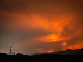 A wildfire burns on a mountain in the distance east of Cache Creek, B.C.