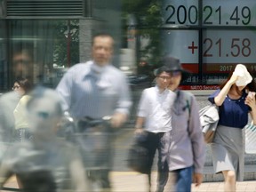 People walk past an electronic stock board showing Japan's Nikkei 225 index at a securities firm in Tokyo Wednesday, July 19, 2017. Shares were mostly higher in Asia on Wednesday after a mixed finish on Wall Street. Investors turned their focus to policy meetings by central bank boards in Japan and the EU.  (AP Photo/Eugene Hoshiko)