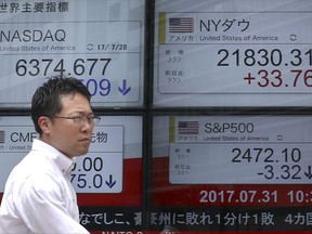 A man walks past an electronic stock indicator of a securities firm in Tokyo, Monday, July 31, 2017. Shares were mixed in Asia early Monday, with Chinese markets shrugging off weaker factory output indicators while Japan's Nikkei index sagged thanks to a surge in the value of the yen. (AP Photo/Shizuo Kambayashi)
