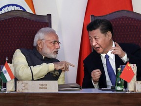 In this Oct. 16, 2016, file photo, Indian Prime Minister Narendra Modi, left, talks with Chinese President Xi Jinping at the BRICS summit in Goa, India. India and China have agreed to pull back their troops from a face-off in the high Himalayas where China, India and Bhutan meet, signaling a thaw in the monthslong standoff, India's government said Monday, Aug. 28, 2017. (AP Photo/Manish Swarup, File)