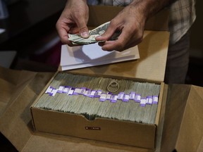 In this June 27, 2017, photo, Jerred Kiloh, owner of the Higher Path medical marijuana dispensary, prepares his monthly tax payment, $40,131.88 in cash in Los Angeles. For Kiloh, the cash is a daily hassle. It needs to be counted repeatedly to safeguard against loss. State and local taxes must be set aside and stored, sometimes for a month or more. When vendors show up, they get paid in cash, too. (AP Photo/Jae C. Hong)