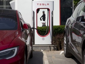 In this Friday, April 14, 2017, file photo, a security guard moves past an electric vehicle charging station in Beijing. Momentum is building worldwide for electric cars thanks to rising government fuel economy standards and climate concerns. Automakers are jumping on board. But selling those cars will be difficult unless the world builds more charging stations.