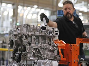 A Ford employee assembles a two liter diesel engine,  at the Ford Dagenham diesel engine plant in London, Friday, July 21, 2017. Ford's Dagenham diesel engine plant is a marvel of mechanization _ a steel and chrome hangar full of LED lighting, robots and computer-controlled machine tools. The U.S. carmaker has invested $2.5 billion in the plant, where 3,150 people churn out an engine every 30 seconds.   (AP Photo/Frank Augstein)