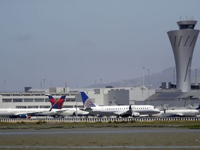 FILE - In this July 11, 2017 file photo, departing and parked aircraft intersect at San Francisco International Airport in San Francisco. Federal officials are imposing new rules on nighttime landings at San Francisco airport after a close call last month. The FAA will also require 2 controllers in the tower. The changes come after an Air Canada jet narrowly missed planes on the ground before aborted an off-line landing on July 7, 2017. (AP Photo/Marcio Jose Sanchez, File)
