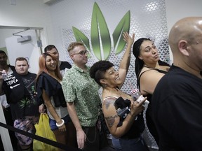 FILE- In this July 1, 2017 file photo, people wait in line at the Essence cannabis dispensary in Las Vegas. A judge cleared the way Thursday, July 17, for Nevada to allow more businesses to move marijuana from growers to stores in an effort to keep up with overwhelming demand since recreational pot sales began last month. (AP Photo/John Locher, File)