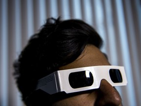 A man models a pair of eclipse viewing glasses for a photograph, in Toronto on Thursday, August 17, 2017. Demand seems to be eclipsing supply for the specialized glasses eclipse viewers will use to observe Monday's solar eclipse event. THE CANADIAN PRESS/Giordano Ciampini