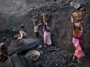 In this Jan. 7, 2011, file photo, people carry baskets of coal scavenged illegally at an open-cast mine in the village of Bokapahari in the eastern Indian state of Jharkhand where a community of coal scavengers live and work. Within the wild energy market of the world's second-most populous nation, predictions are proving tricky. India had been projected to become a carbon-belching behemoth, fueled by thermal power plants demanding ever more coal for decades to come. Now, some analysts are saying that may not happen. (AP Photo/Kevin Frayer, File)