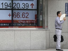A man uses a paper fan while standing in front of an electronic stock board of a securities firm in Tokyo, Friday, Aug. 25, 2017. Asian stocks were mostly higher Friday as market players watched for comments at a central banks' annual meeting later in the global day. (AP Photo/Koji Sasahara)