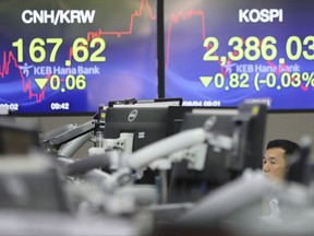 A currency trader watches monitors near the screens showing the Korea Composite Stock Price Index (AP Photo/Lee Jin-man)