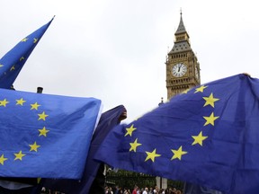 People hold up EU flags while the last bell bongs at Elizabeth Tower in London, Monday, Aug. 21, 2017. At noon, Big Ben's famous bongs sounded for the last time before major conservation works are carried out. The Elizabeth Tower, home to the Great Clock and Big Ben, is currently undergoing a complex programme of renovation work that will safeguard it for future generations. While this vital work takes place, the Great Bell's world famous striking will be paused until 2021 to ensure the safety of those working in the Tower.(AP Photo/Leonore Schick)