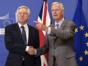 FILE - A Monday July 17, 2017 file photo of EU chief Brexit negotiator Michel Barnier, right, welcoming British Secretary of State, David Davis, for a meeting at the EU headquarters in Brussels. The British government is fighting back against criticisms that it is divided and unprepared for Brexit, announcing it will publish a set of detailed proposals on customs arrangements, the status of the Ireland-Northern Ireland border and other issues. The Department for Exiting the European Union said Sunday, Aug. 13, 2017, that it would release the first set of position papers this week, more than a year after Britons voted in a referendum to leave the European Union.(AP Photo/Geert Vanden Wijngaer, File)