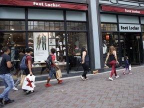 In this Friday, Aug. 25, 2017, photo, shoppers walk past a Foot Locker store in Boston. On Tuesday, Aug. 29, 2017, the Conference Board releases its July index on U.S. consumer confidence. (AP Photo/Charles Krupa)