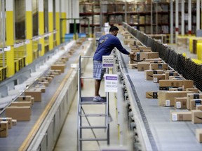 An Amazon employee makes sure a box riding on a belt is not sticking out at the Amazon Fulfillment center in Robbinsville Township, N.J.