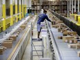 An Amazon employee makes sure a box riding on a belt is not sticking out at the Amazon Fulfillment center in Robbinsville Township, N.J.